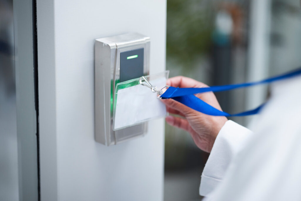hand-key-card-and-scan-for-security-door-entranc-2025-04-06-08-35-17-utc A person holds a blank ID badge on a blue lanyard near an electronic card reader, preparing to scan it for access through a secured door.